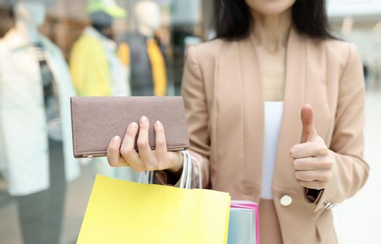 Close-up of woman hold wallet full with cash, show thumbs up gesture with finger. Enough money for shopping. Wealth, rich, shopaholic, store, mall concept