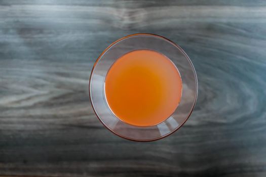 Orange fresh coctail juice in glass up view on wodden background.