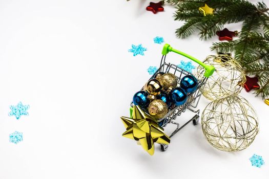 Christmas toys in the buyer's basket. Full shopping cart. Balls, bells next to the shopping cart. The concept of gifts and purchases before the New Year. White background.