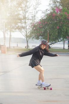 Asian women on skates board outdoors on beautiful summer day. Happy young women play surfskate at park on morning time. Sport activity lifestyle concept
