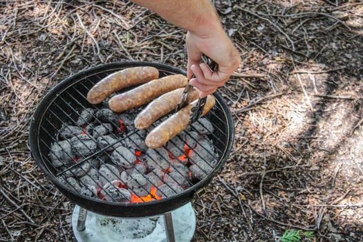 Hot BBQ Grill With Ribs, Bratwurst And Sausages, Close Up, Top View. Green Lawn In The Background. Outdoor Party or Picnic Concept.