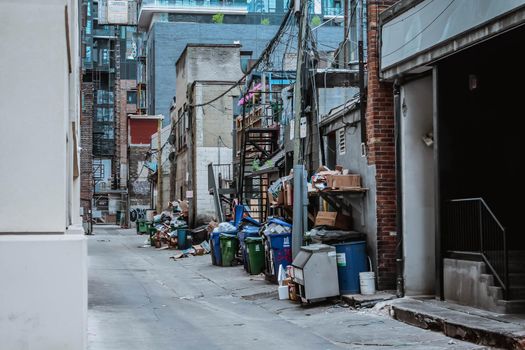 Large garbage pile inside black bags and green containers on street