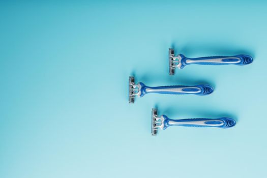 Blue shaving machine with sharp blades on the background of ice cubes close-up. The concept of cleanliness and frosty freshness