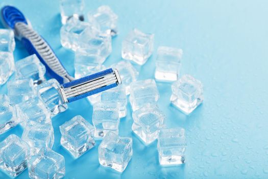 Shaving machine on a blue background with ice cubes. The concept of cleanliness and frosty freshness