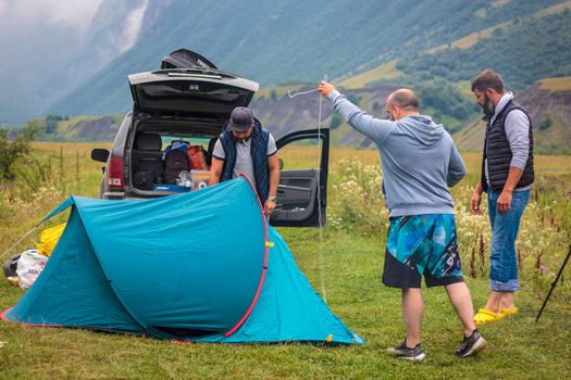 A company of friends is resting in the mountains, setting up a tent. Mountains of the Caucasus. Russia Ossetia Vladikavkaz August 15, 2020.