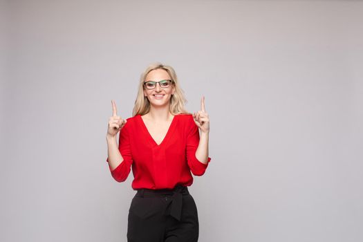 Front view of elegant successful female wearing smart outfit and glasses and posing on isolated background. Intelligent woman with folded arms looking at camera in studio. Concept of job and business.