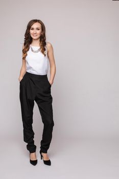 Front view of elegant successful female wearing smart outfit and glasses and posing on isolated background. Intelligent woman with folded arms looking at camera in studio. Concept of job and business.