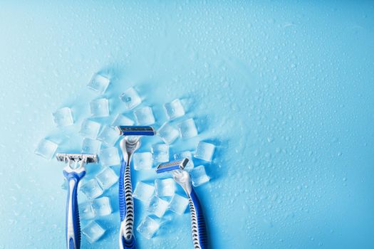Shaving machine on a blue background with ice cubes. The concept of cleanliness and frosty freshness
