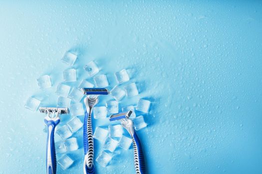 Shaving machine on a blue background with ice cubes. The concept of cleanliness and frosty freshness