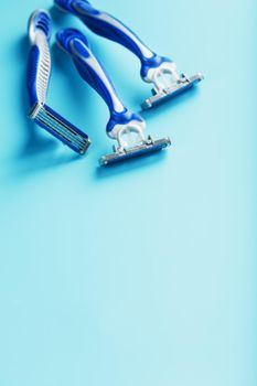 Blue shaving machine with sharp blades on the background of ice cubes close-up. The concept of cleanliness and frosty freshness