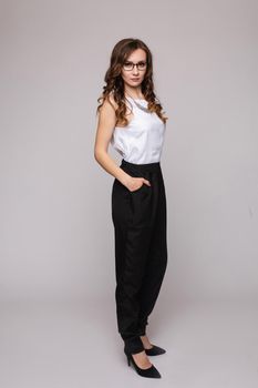 Beautiful young businesswoman in glasses thinking seriously and posing at camera. Blonde pretty lady leaning one hand one other and touching face. Confident girl in red blouse looking thoughtfully.