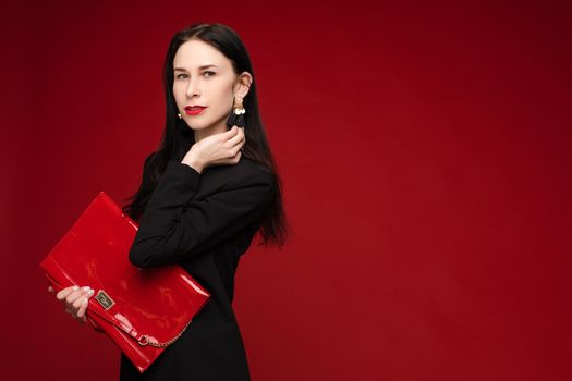 Portrait of young beautiful woman thoughtfully looking down. Brunette model in elegant costume posing at camera . Pretty lady in red sunglasses leaning one hand on other and holding it near face.