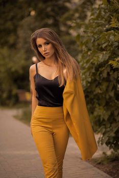 Side view of glamorous brunette posing in smart suit and heels . Concept of beauty and fashion.