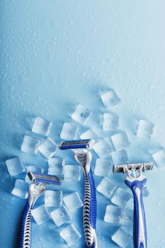 Shaving machine on a blue background with ice cubes. The concept of cleanliness and frosty freshness