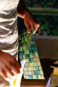 Worker applying mosaic tiles in bathroom, sauna walls. Bathroom renovation.