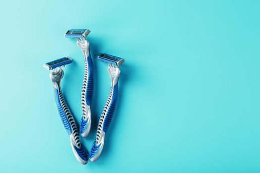 Blue shaving machine with sharp blades on the background of ice cubes close-up. The concept of cleanliness and frosty freshness