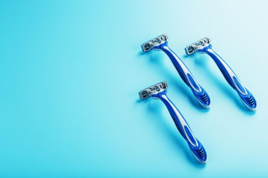 Blue shaving machine with sharp blades on the background of ice cubes close-up. The concept of cleanliness and frosty freshness