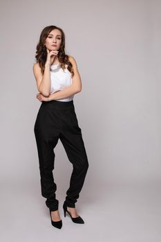 Front view of elegant successful female wearing smart outfit and glasses and posing on isolated background. Intelligent woman with folded arms looking at camera in studio. Concept of job and business.