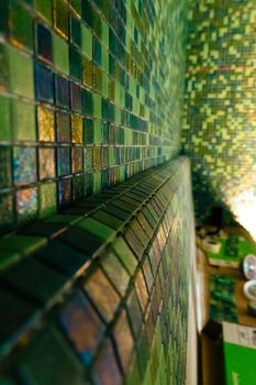 Close up modern green mosaic tiles on wall. Sauna room interior design with mosaic.