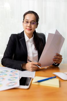 Business women smileing wear glasses holding document paper chart sitting at office. business people using computer PC  at office. Business at home concept.