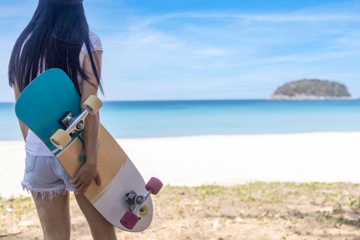 Young women hold surf skate board with beach background. Women stand with surf skate relax and enjoy with tropical beach with copy space
