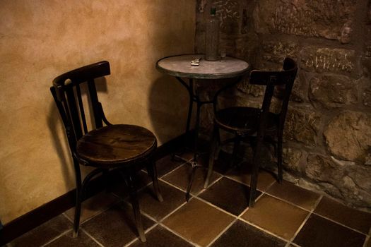 Two chairs and a table with a domino game and a bottle in an antique pub