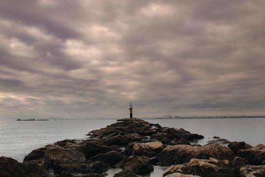 Seascape with a rocky path to a light house in Roses beach in Costa Brava in Catalonia