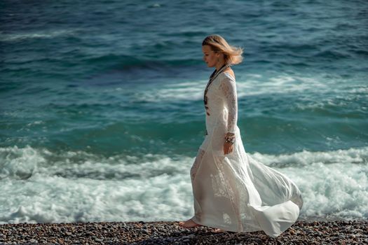 Middle aged woman looks good with blond hair, boho style in white long dress on the beach decorations on her neck and arms