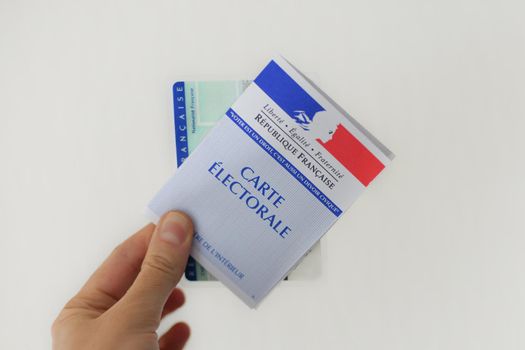 PARIS, FRANCE - MARCH 09, 2020: A Hand holds a french electoral card and an identification card for voting