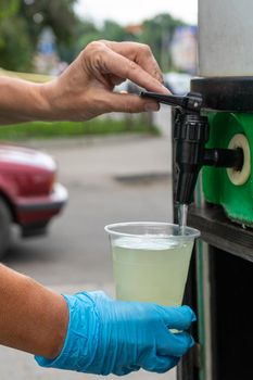 A female salesman pours mohito from a barrel into a disposable glass. Street trade. Clous up