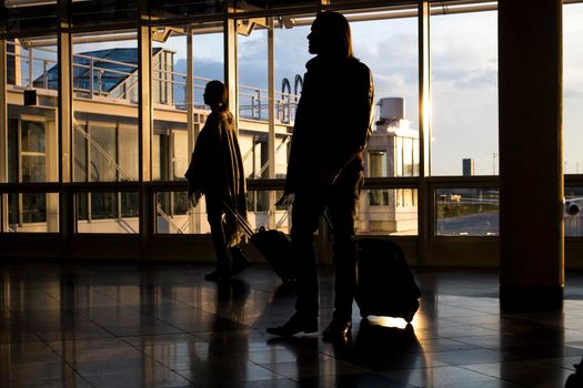 Two travelers inside an airport and the outside view through a showcase