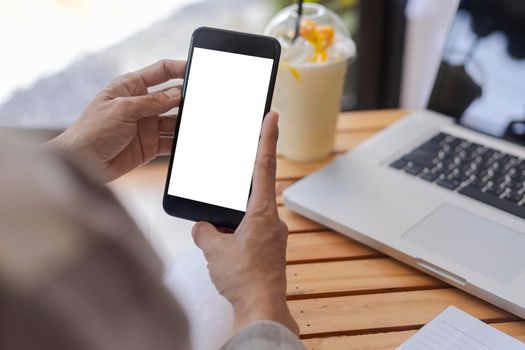 Top view female hands holding smart phone with blank white screen. Women hands workspace, close-up hand holding smartphone blank screen for text and content on wood table background.