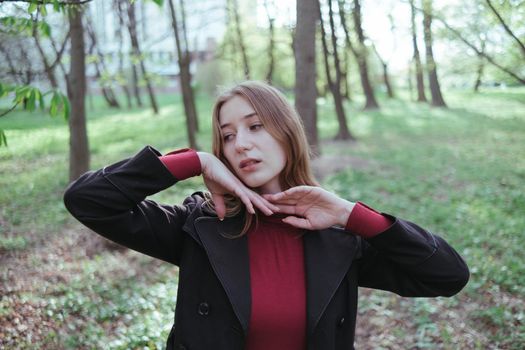 a girl in red golf and a black jacket enjoys spring in the forest