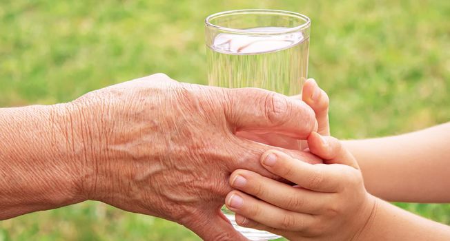 Grandmother giving a glass of clean water to a child. Selective focus. nature.