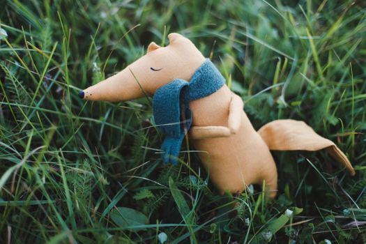 Cute little handmade toy fox in green grass. Childhood, baby, holiday, people, hobby, emotions concepts. High quality photo