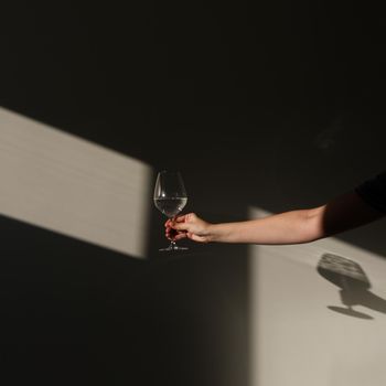 A glass of water on a white background with a shadow. Chiaroscuro from the window. Close-up, copy space.