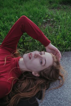 a blonde girl in red lies in the park