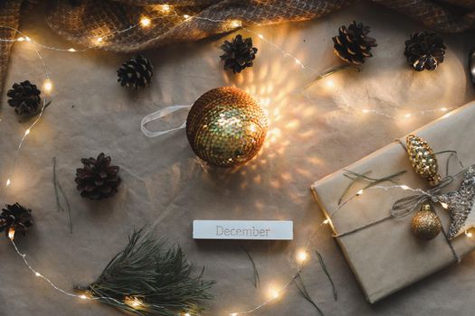 Christmas composition. Gift, fir tree branches, balls on craft paper background. Christmas, winter, new year concept. Flat lay, top view, copy space.