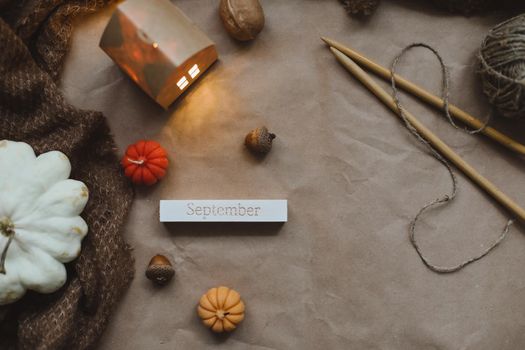 Cozy autumn composition with paper house surrounded by autumn leaves, candles and pumpkin top view. Hygge home decor. Halloween and Thanksgiving concept.
