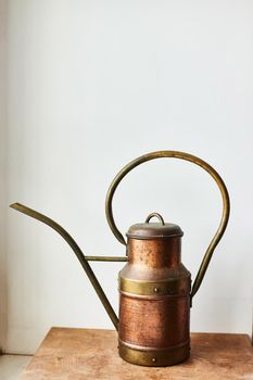 Vintage copper watering can on a wooden stand