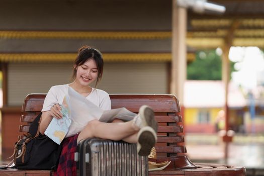 Pretty Young traveler woman looking on maps planning trip at train station. Summer and travel lifestyle concept
