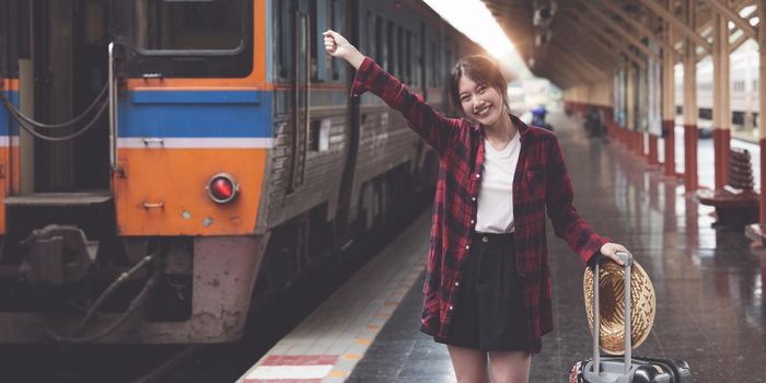 Happy Young traveler woman looking for friend planning trip at train station. Summer and travel lifestyle concept