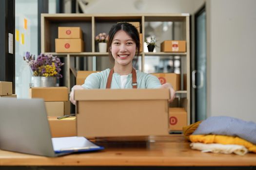 Startup small business entrepreneur SME, asian woman packing box. Portrait of young Asian small business owner in home office, online sell marketing delivery, SME e-commerce telemarketing concept.