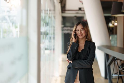 Entrepreneur young asian woman making call on mobile phone, business woman arms crossed on workplace at her office.