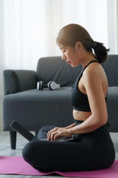 Young woman practicing yoga follow teacher in laptop online class at home. Calmness and relax concept