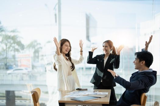 Young multiethnic diverse creative asian group huddle and high five hands together in office workshop with success or empower expression in teamwork. Young asian marketing team with copy space.