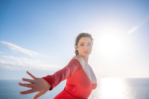 Closeup video portrait of sensual young brunette woman in red dress, happily dancing outdoors isolated on blurry sea background with natural bokeh in soft warm sunset backlight