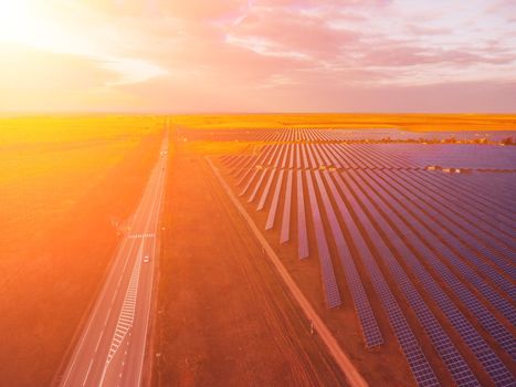 Aerial top view of a solar panels power plant. Photovoltaic solar panels at sunrise and sunset in countryside from above. Modern technology, climate care, earth saving, renewable energy concept