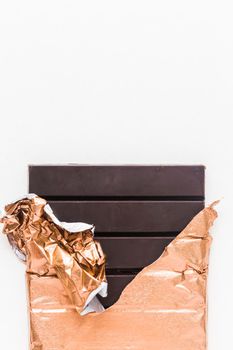 delicious chocolate bar wrapped golden foil white background