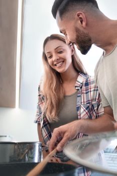 close up. young husband and wife looking into a pot of soup . photo with copy space